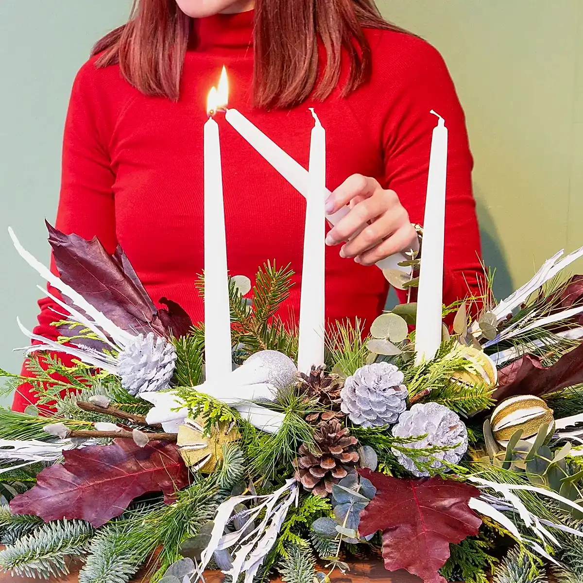 Centro de mesa navideño a domicilio en madrid con velas y en tonos plateados. Sobre una mesa.