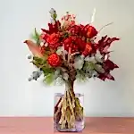 Ramo de flores navideño en tonos rojos y cálidos. Perfecto para regalar a domicilio en Madrid.