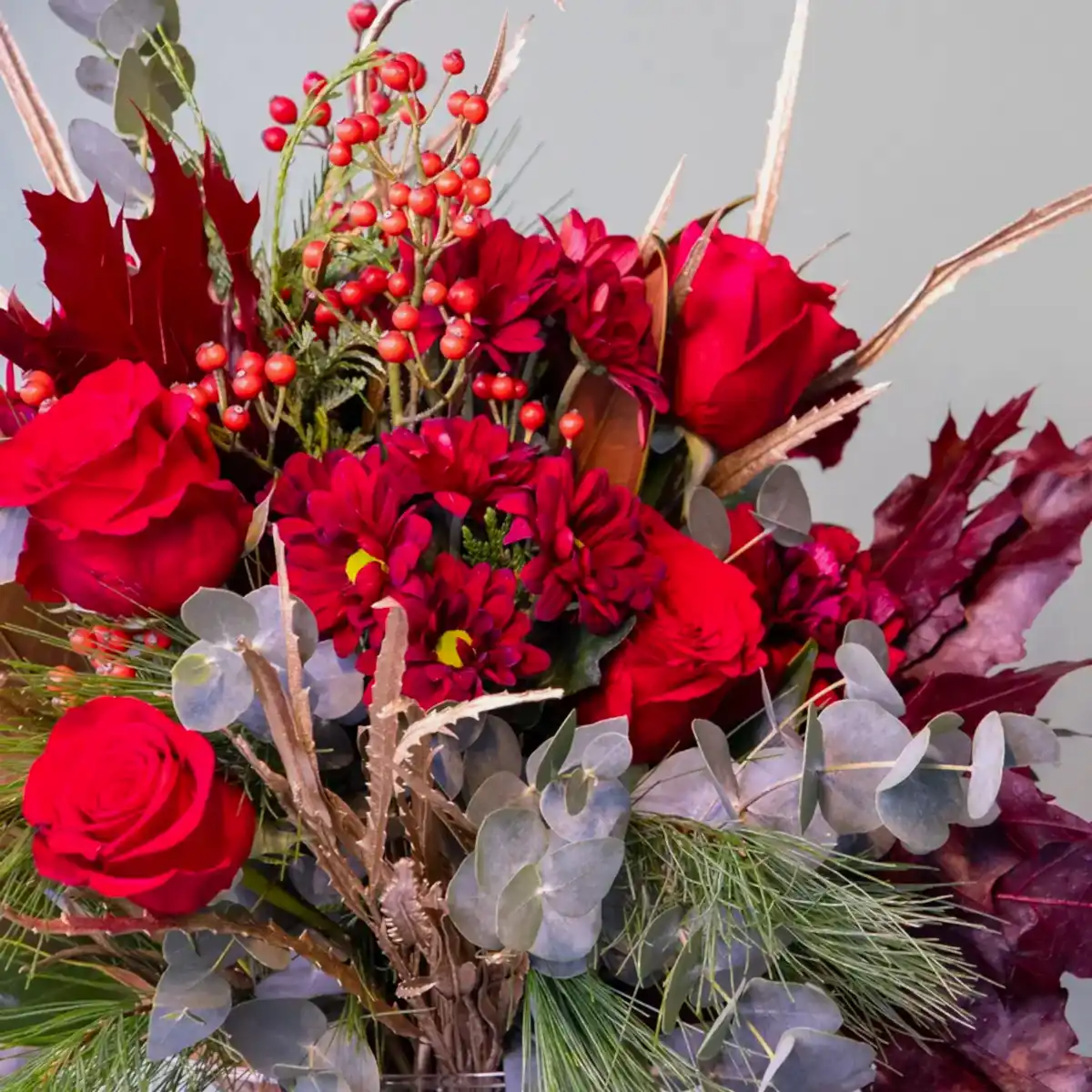 Detalle de Ramo de flores navideño en tonos rojos y cálidos. Perfecto para regalar a domicilio en Madrid.